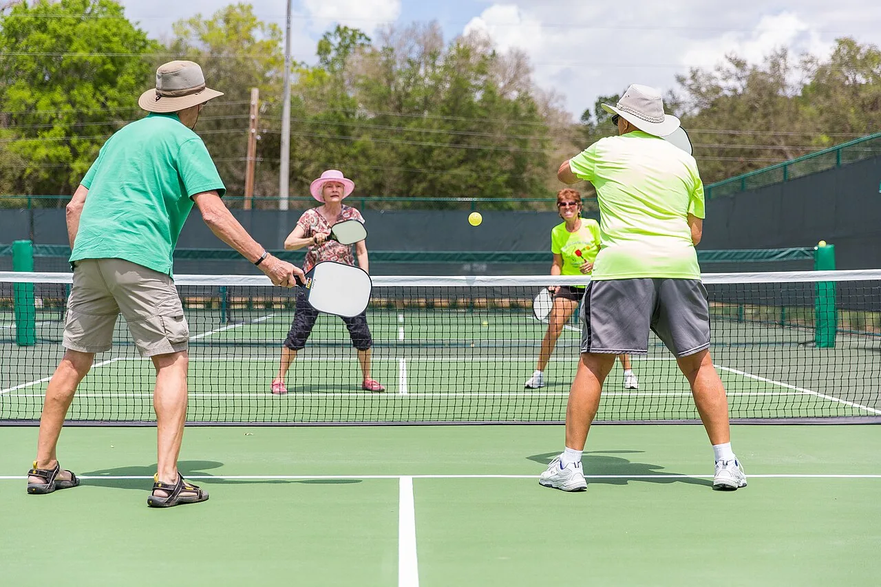 Pickleball players of mixed ages rallying during a doubles game