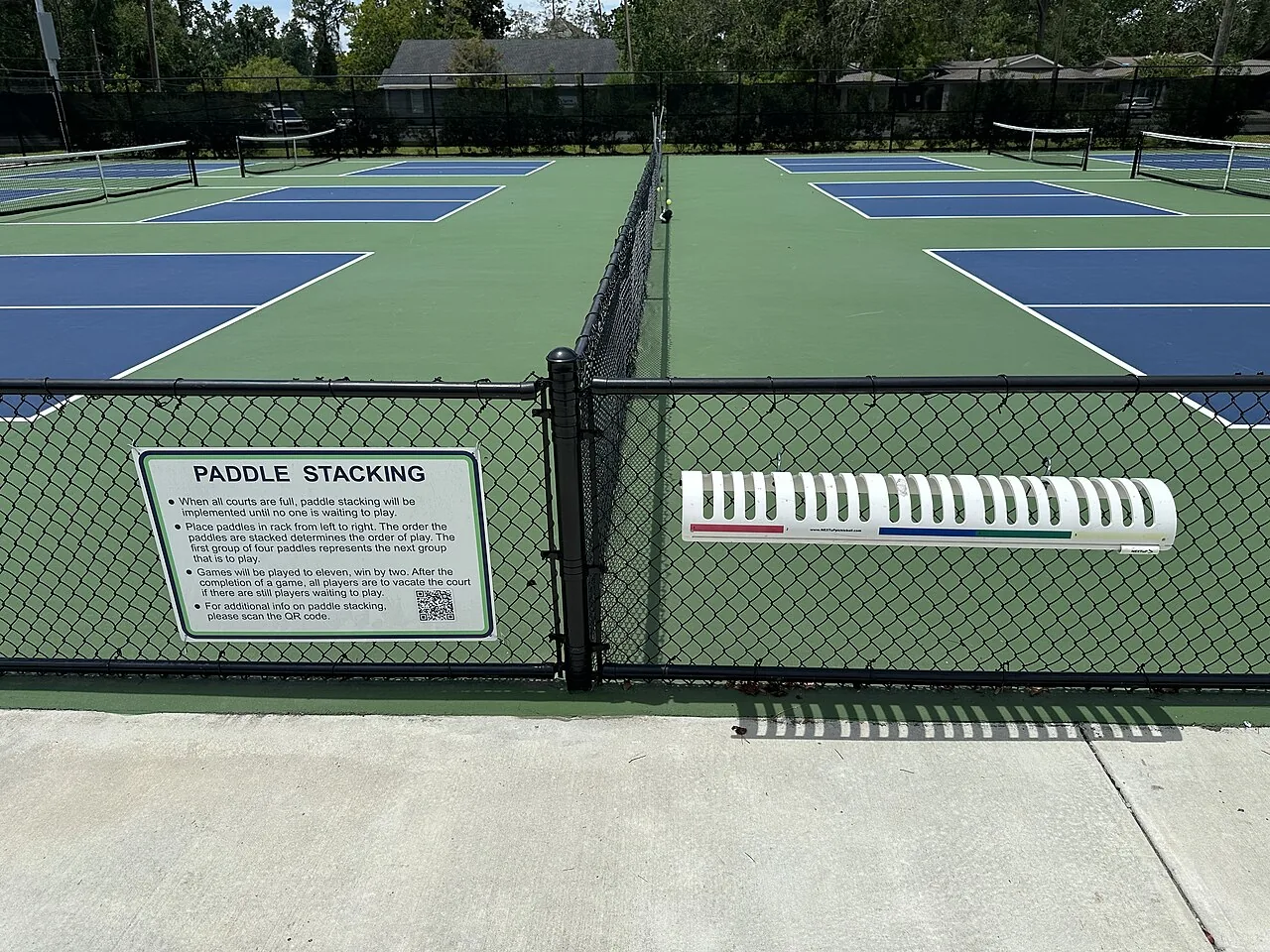 Pickleball paddles and a ball resting on a court
