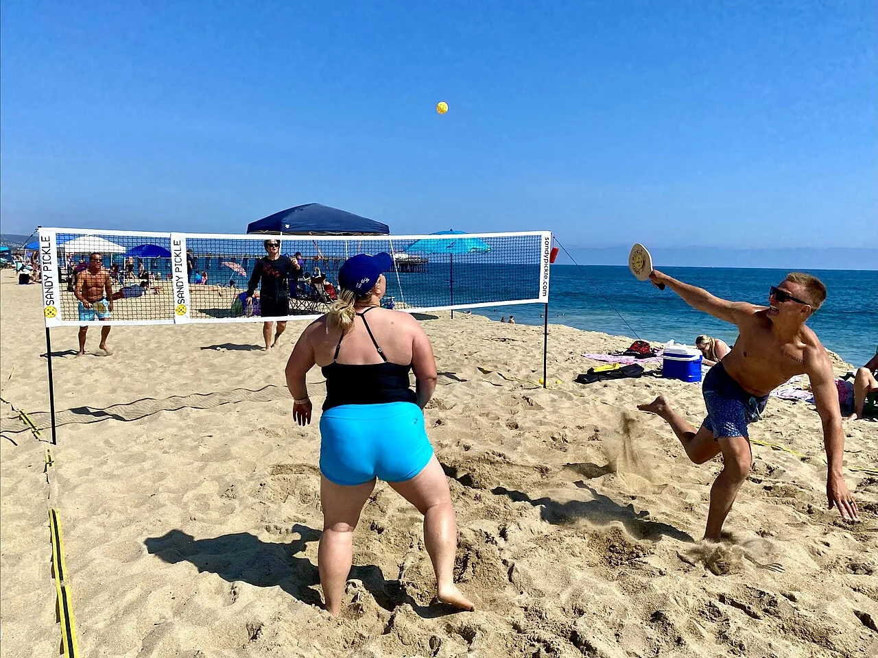 Players rallying during a doubles pickleball match on an outdoor court