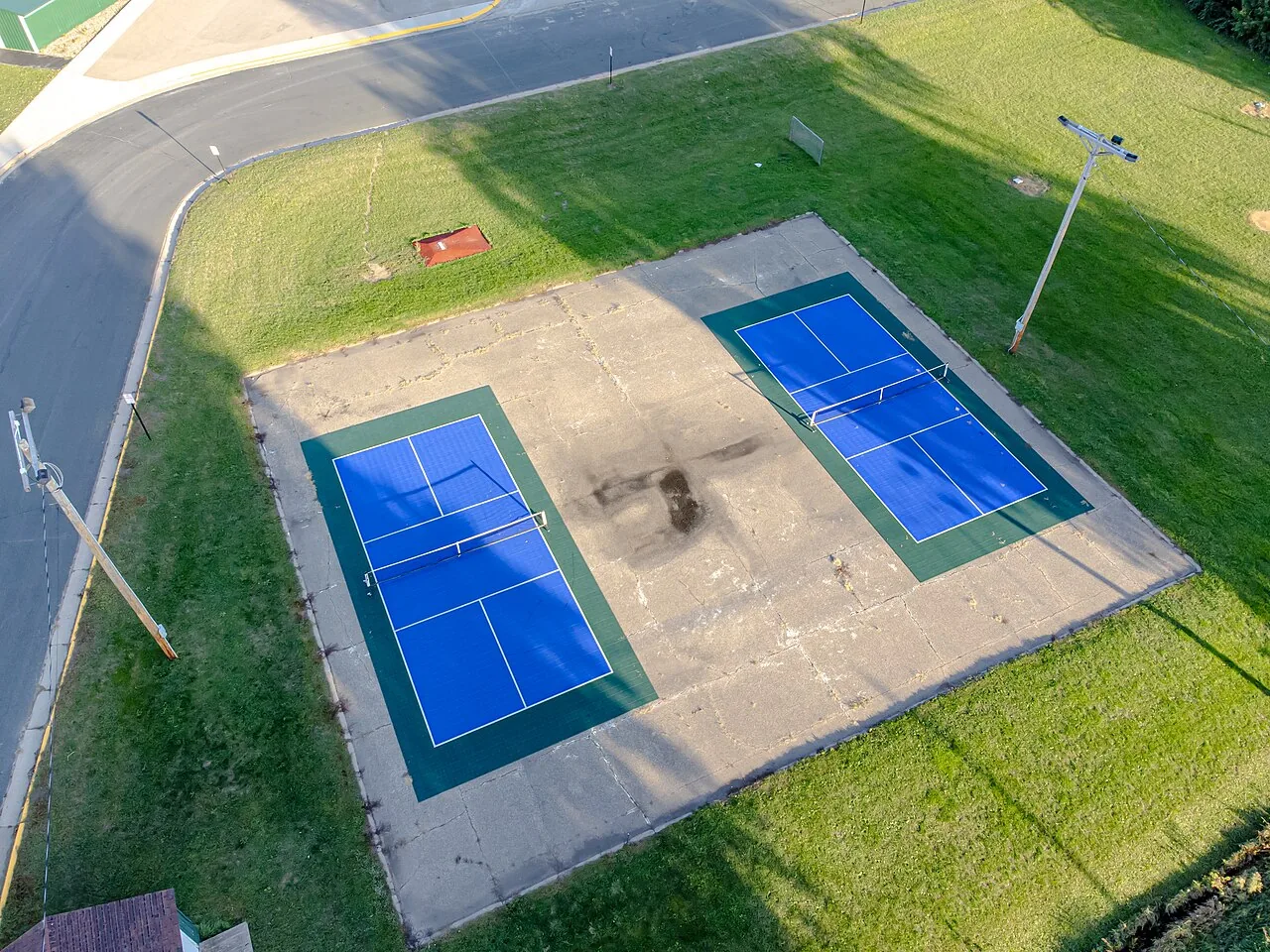 An indoor pickleball court with a hard playing surface and overhead lighting