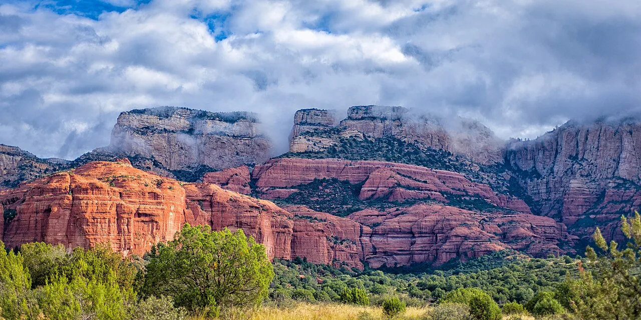 A hiker standing on top of the narrow Devil's Bridge arch above Red Rock Country