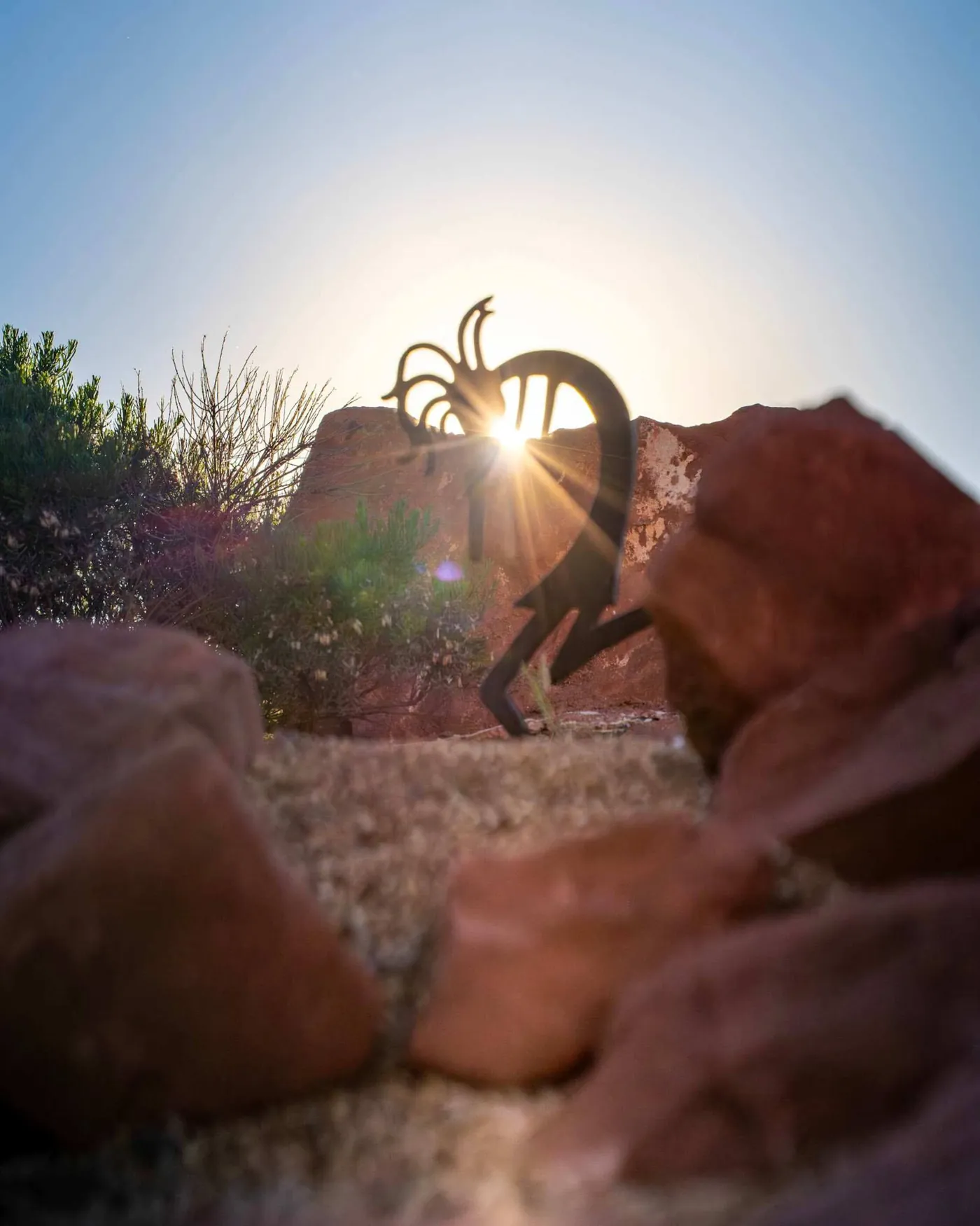 Kokopelli metal sculpture in the garden at sunset
